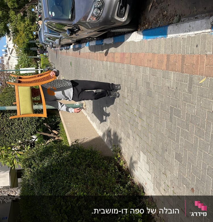 אדם נושא כיסא עץ ברחוב ליד מכוניות חונות